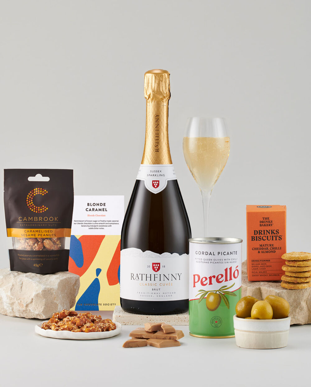 Bottle of Classic Cuvee 2018 Surrounded by a Selection of Smartly Packaged Foods.