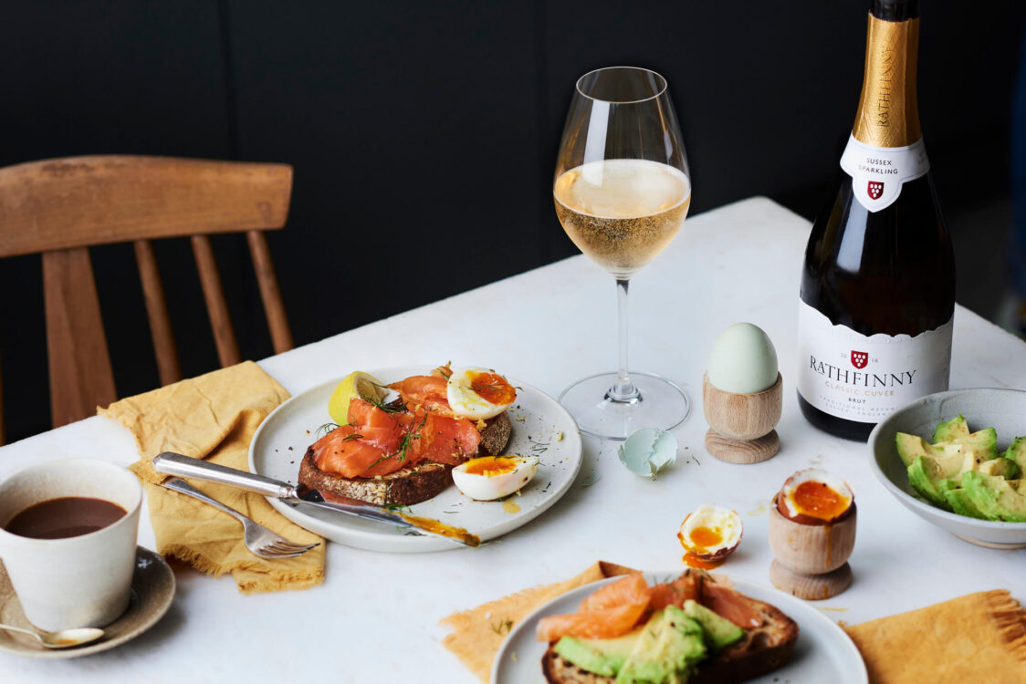 A table set for brunch with a glass of Sussex Sparkling wine, toast, salmon, eggs and avocado